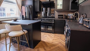 Una cocina moderna con una isla central, taburetes de bar, horno empotrado y un amplio ventanal.