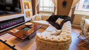 Una sala de estar moderna con un televisor de pantalla plana grande, una chimenea, un sofá modular y una mesa de centro.