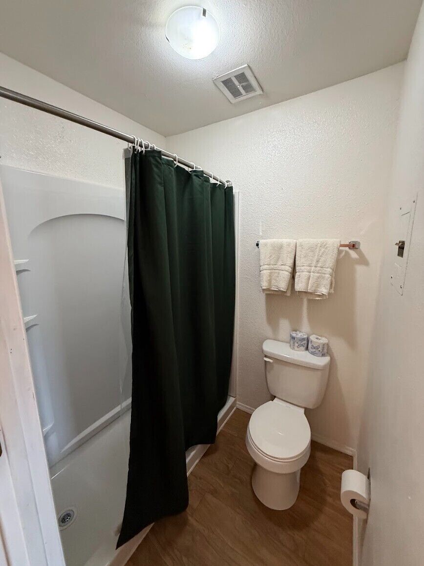 A small bathroom with a shower curtain, toilet, and towel rack.