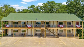 A two-story motel with a green roof, multiple rooms, and a parking lot.