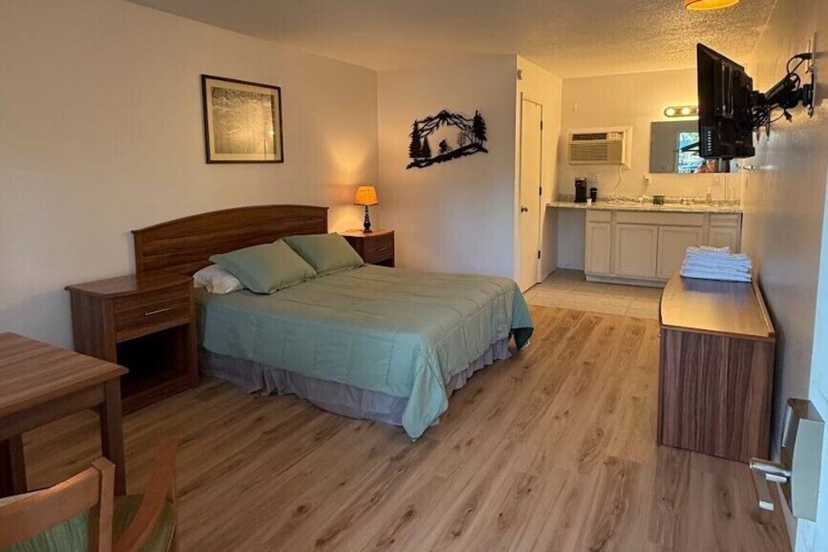 Il s’agit d’une pièce de taille modeste, comprenant un lit, une table de chevet, une chaise et un petit bureau avec une autre chaise. On y trouve également une kitchenette équipée d’un évier, d’une cuisinière et de placards.
