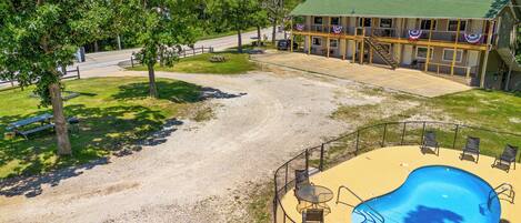 A two-story building with a pool area, outdoor seating, and a picnic table.