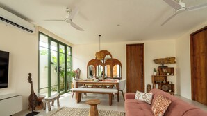 A living room with a sofa, a dining table, and a TV. - Boutique 4BR Villa With Private Pool & Balcony Suite (Kuta Utara)
