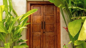 A wooden double door with a stone wall and large green plants. - Boutique 4BR Villa With Private Pool & Balcony Suite (Kuta Utara)