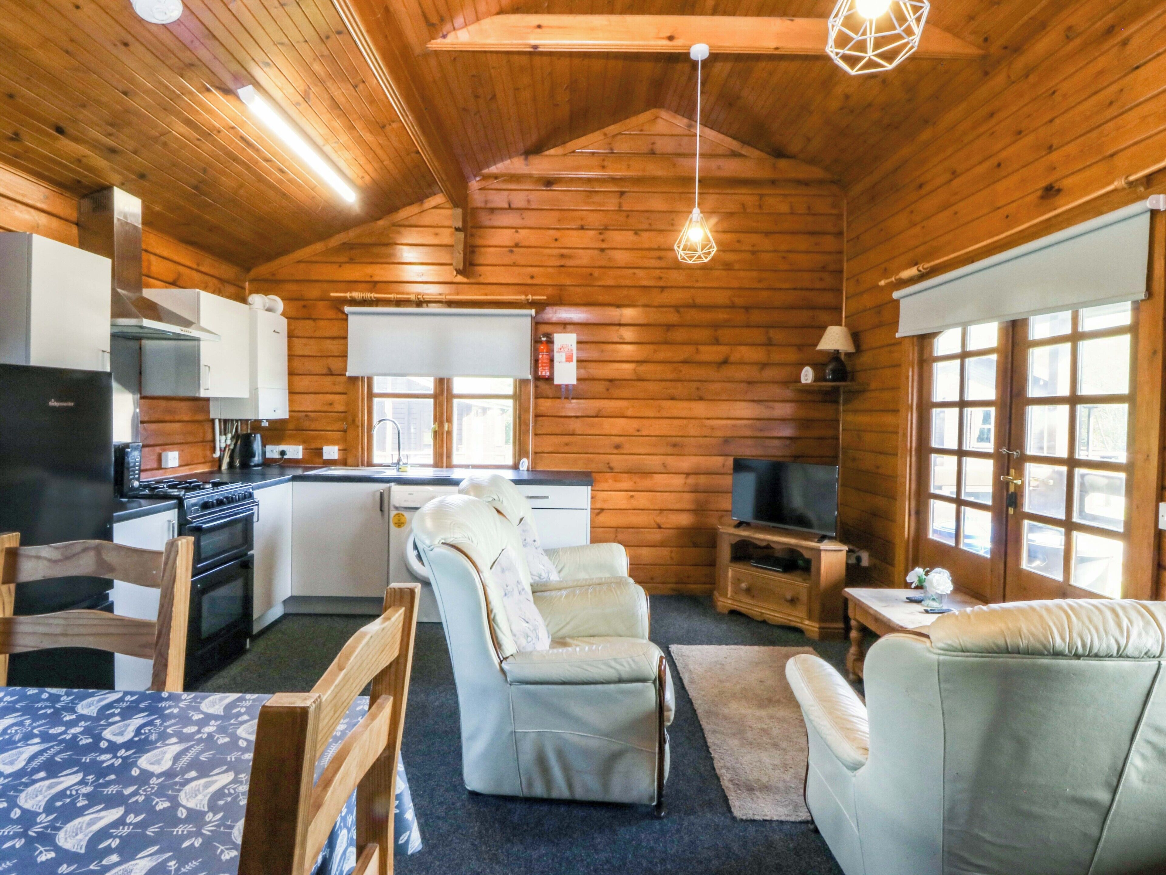 A log cabin interior with a kitchen, dining area, and seating.