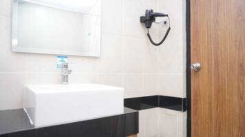 Un baño con un lavamanos blanco, un espejo, un perchero negro y una puerta de madera.