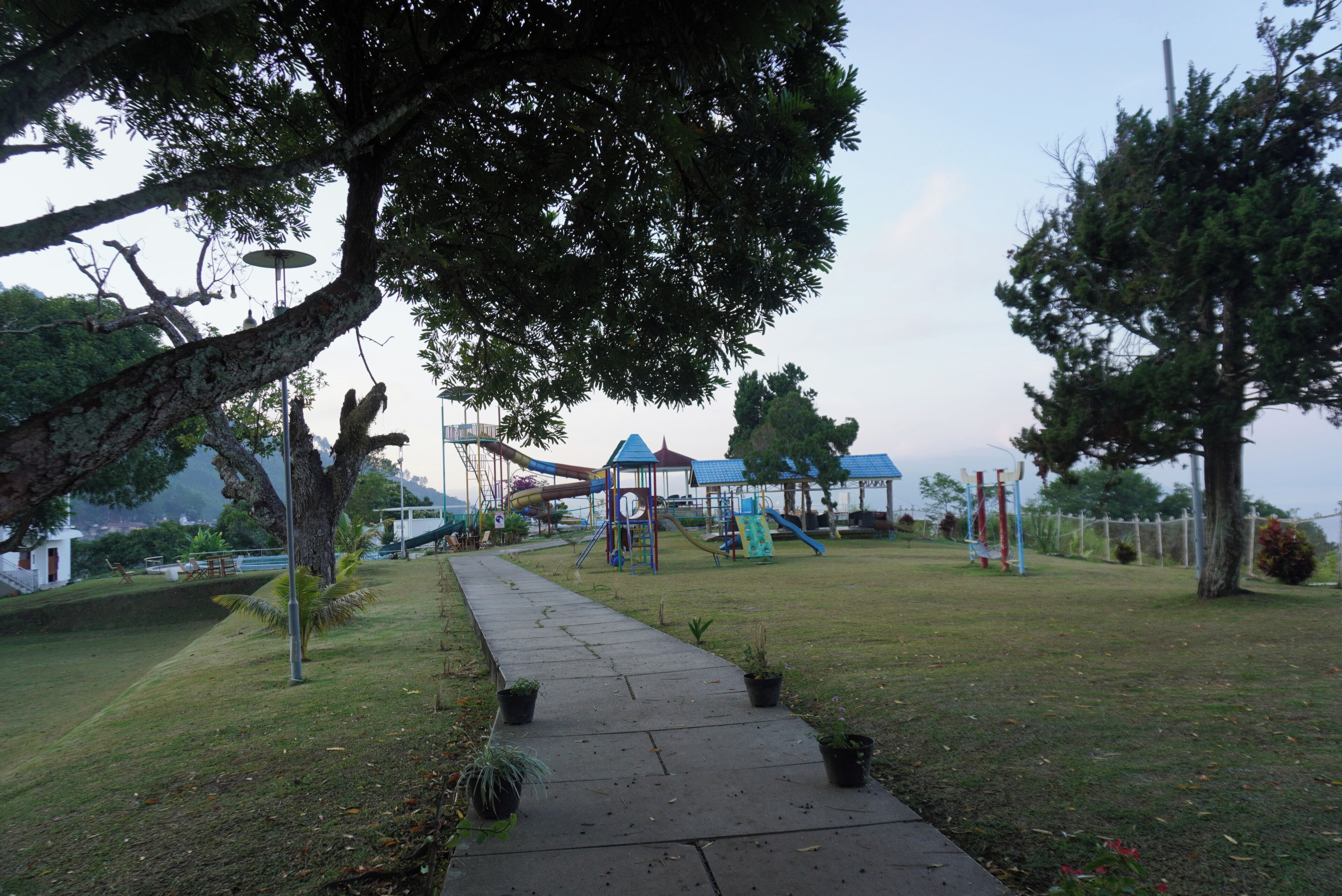 A park with a playground, a pathway, and trees.