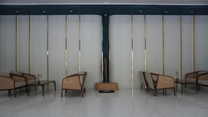 A waiting area with wicker chairs, a small table, and a wall with vertical panels. - Patra Parapat Hotel (Parapat)