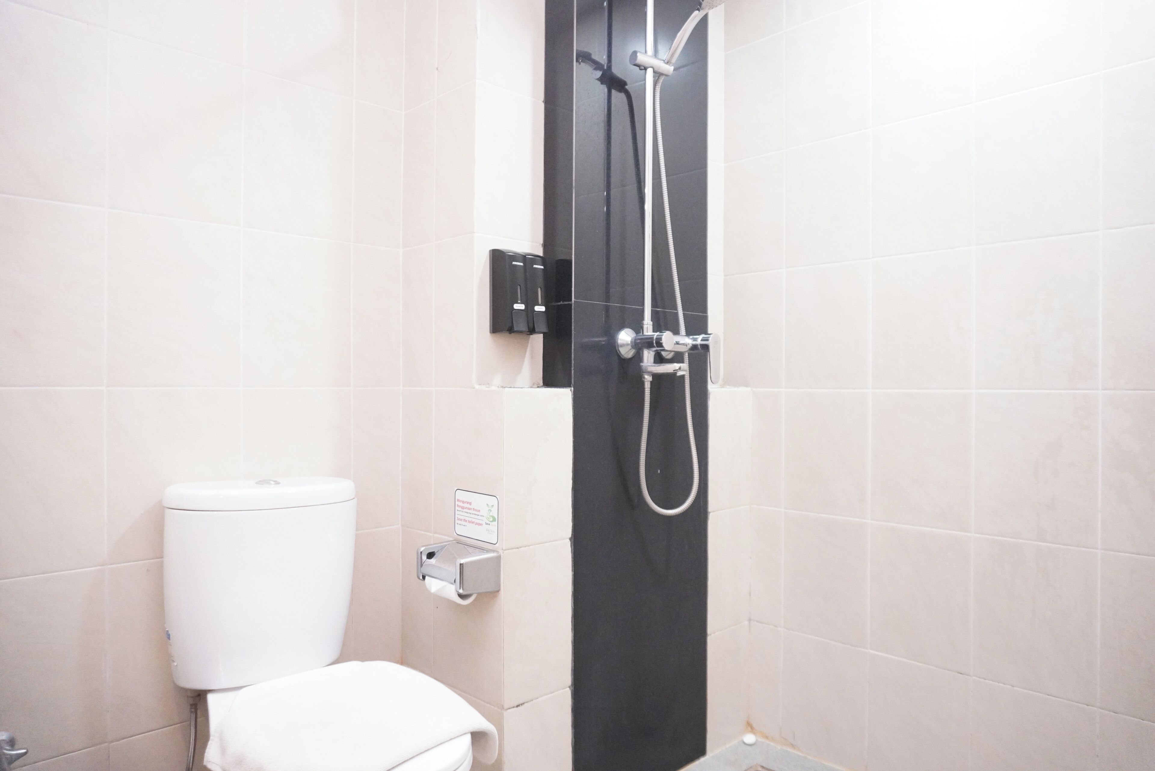 Une salle de bain équipée de toilettes, d’une douche et d’un sèche-mains.