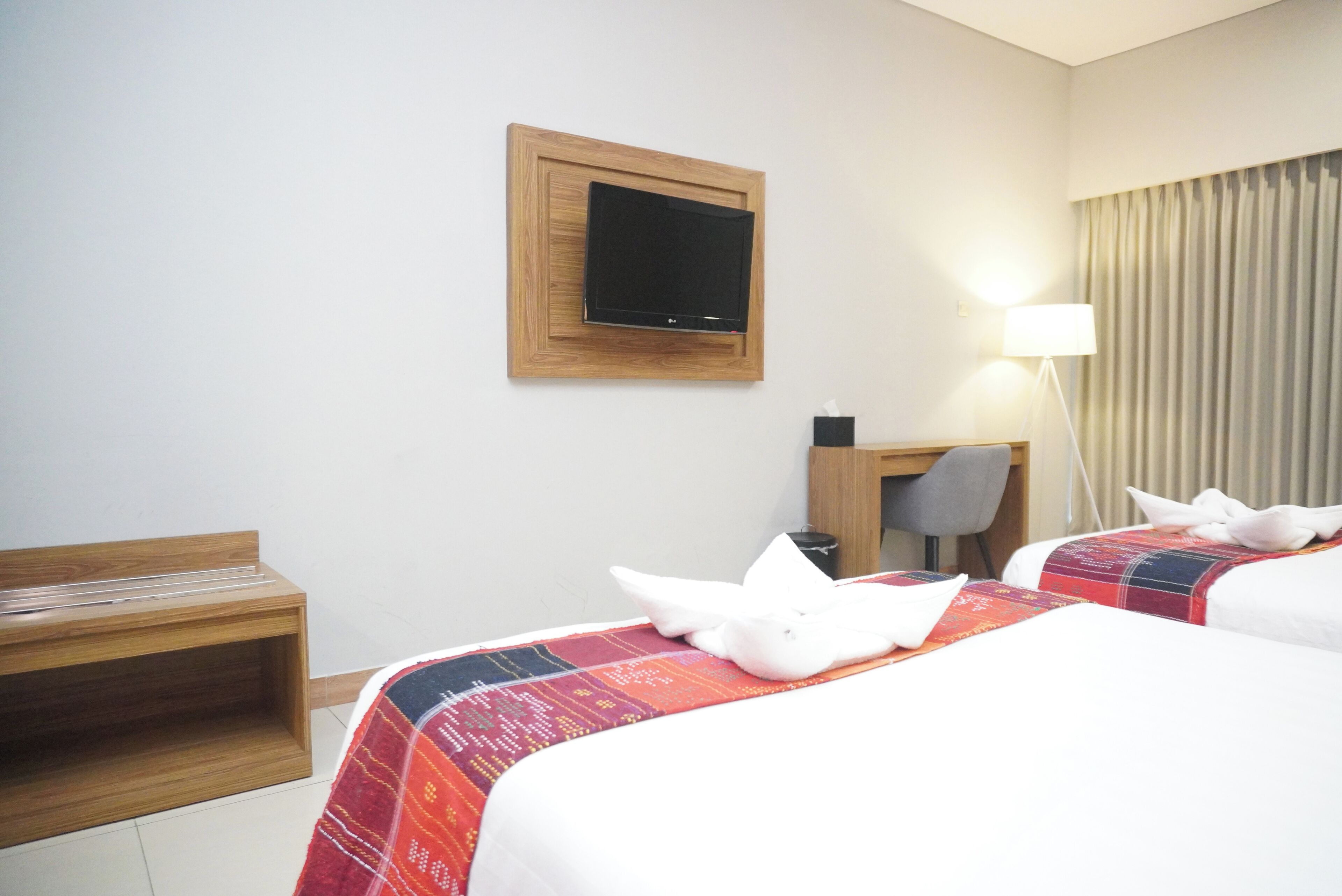 Une chambre d’hôtel avec deux lits, un bureau, une chaise, une télévision et une lampe.