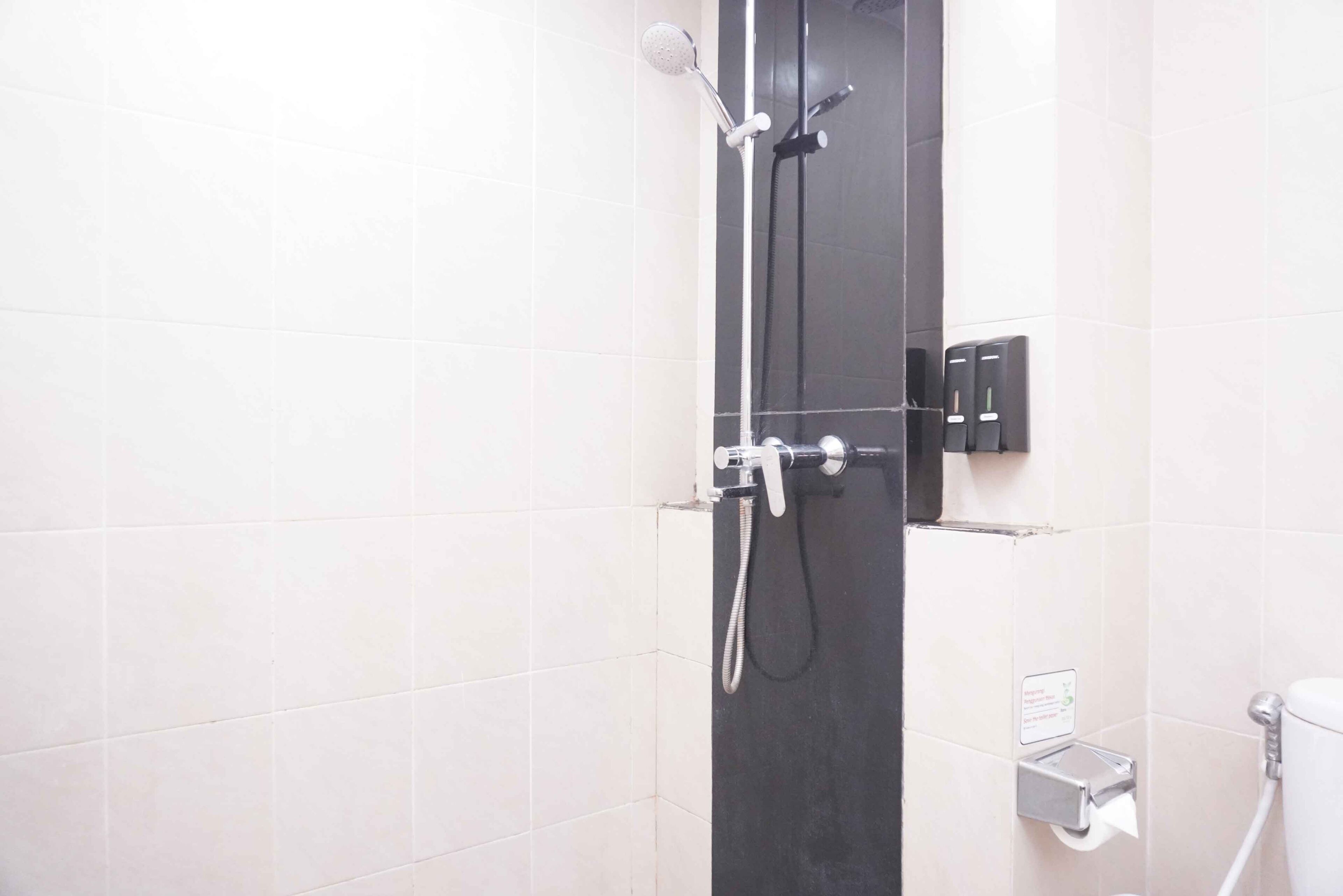 Een badkamer met douche, toilet en handdroger.