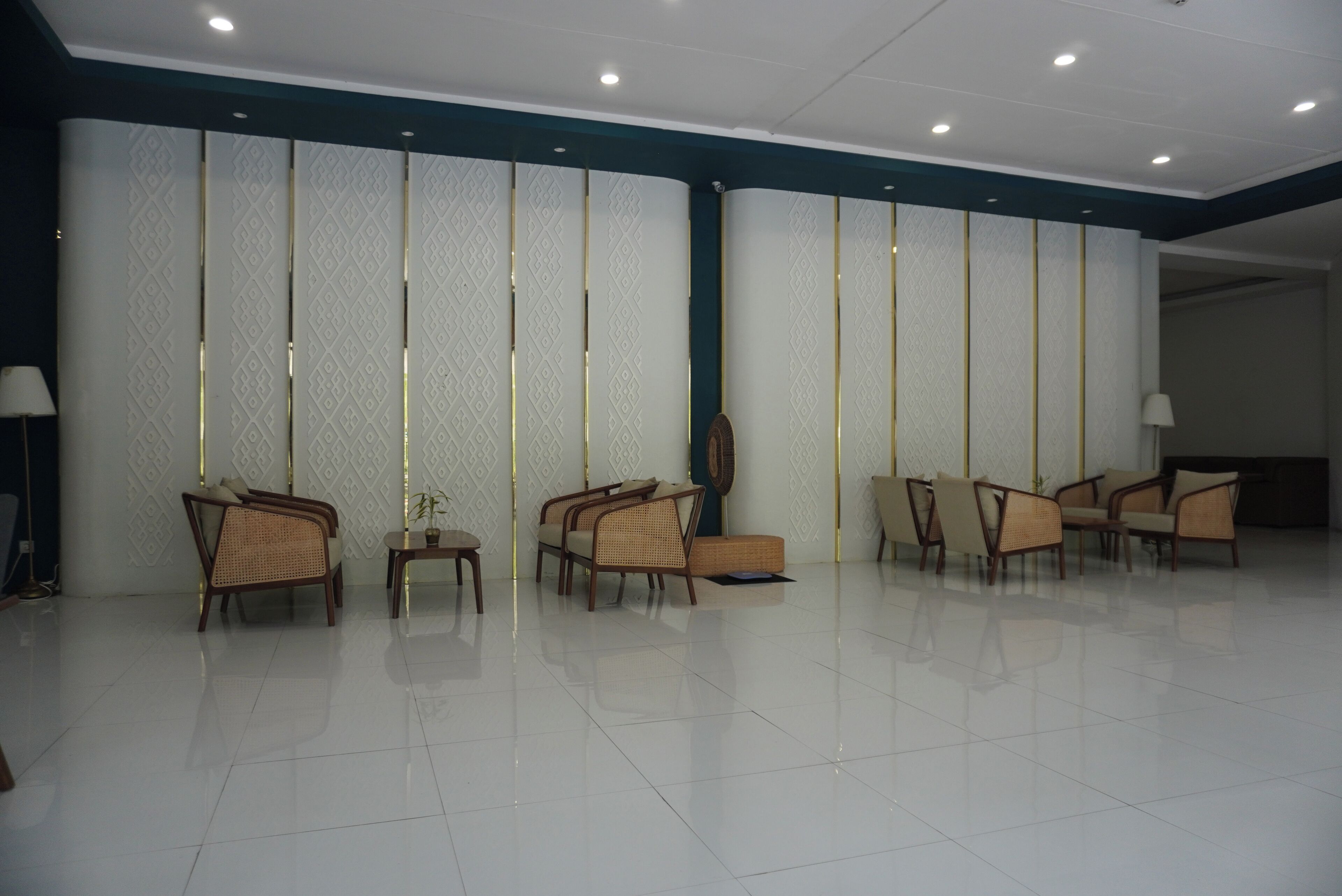 A spacious lobby with a row of chairs, a reception desk, and a patterned wall.
