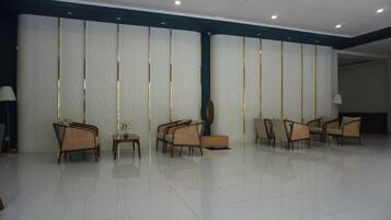 A spacious lobby with a row of chairs, a reception desk, and a patterned wall.