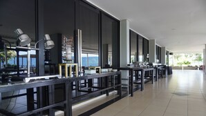 A modern hotel lobby with long tables, large windows, and a view of the outdoors. - Patra Parapat Hotel (Parapat)