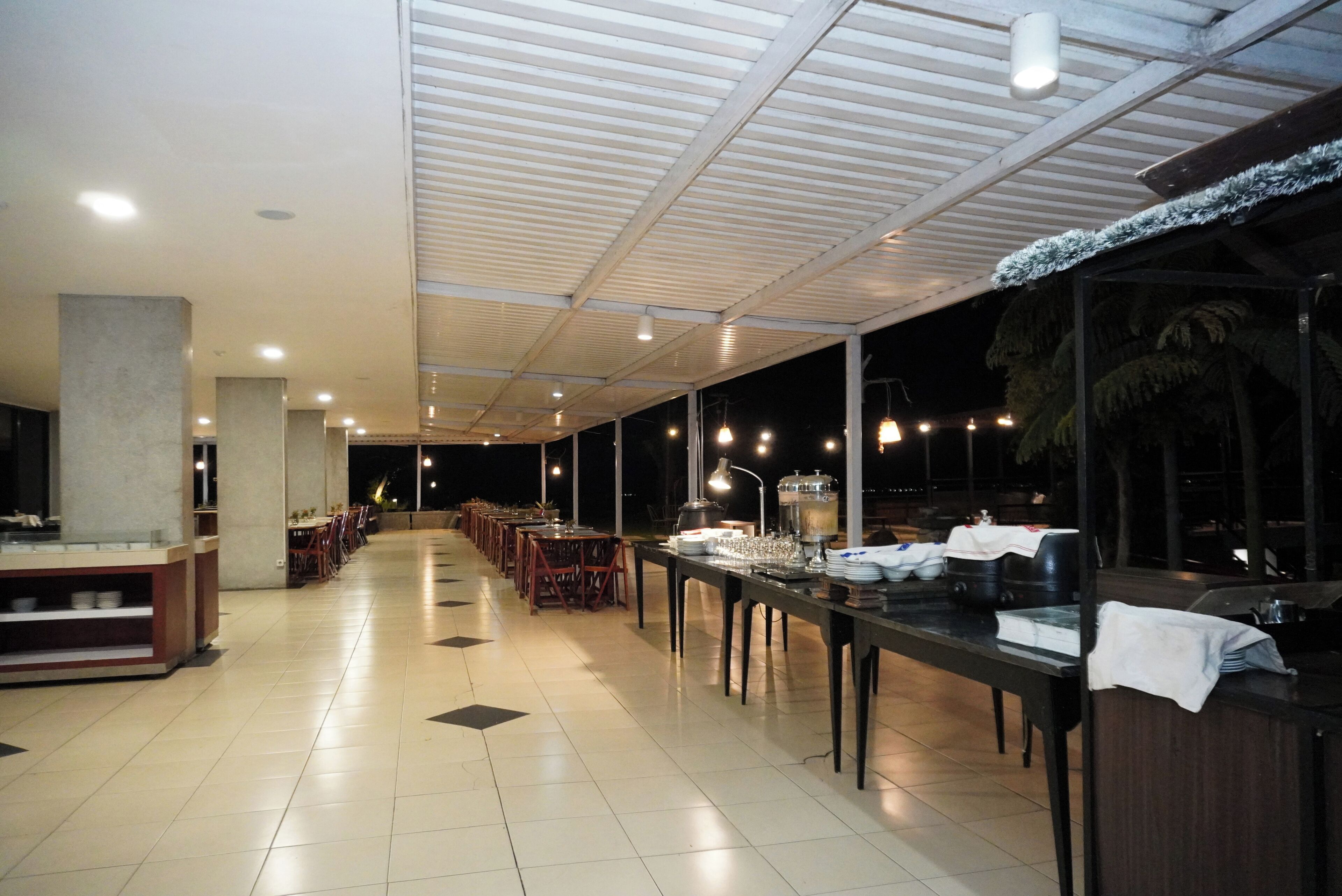 A spacious indoor dining area with long tables, chairs, and a ceiling with lights.