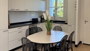 Een moderne keuken met witte kasten, een ronde eettafel en zwarte stoelen.