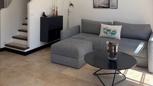 Een moderne woonkamer met een grijze hoekbank, een zwarte salontafel en een trap.