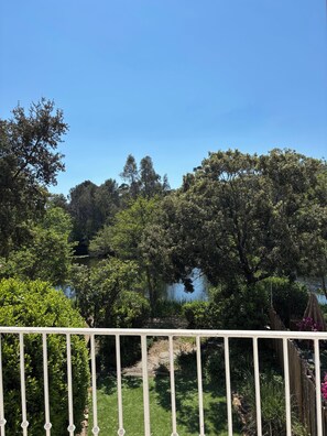 Ein Garten mit Teich, Bäumen und einem weißen Zaun.