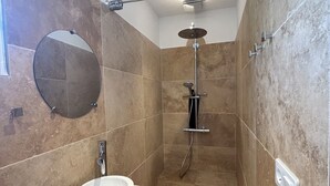 Een moderne badkamer met een douche, een wastafel en een spiegel.