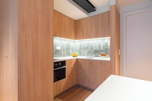 Una cocina moderna con armarios de madera, horno empotrado y ventana con vistas.