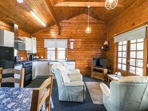 Ein rustikaler Holzblockhaus-Innenraum mit Küche, Essbereich und Sitzgelegenheiten.