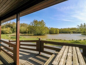 Eine Holzterrasse mit Blick auf einen Fluss und Bäume.