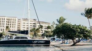 Un yate llamado 'Lady Lynsey' amarrado en una playa, con un hotel al fondo.