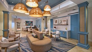 Un vestíbulo amplio con un sofá curvo, varias sillas, una zona de comedor y una encimera de cocina.