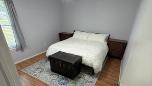 Ein Schlafzimmer mit Bett, einer Kommode, einem Deckenventilator und einem Fenster mit Vorhängen.