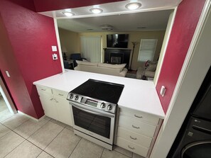 Een kleine keuken met een fornuis, oven en witte kasten.