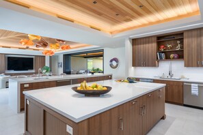 Eine moderne Küche mit einer großen Kochinsel, Holzschränken und einer Decke aus Holzbalken.