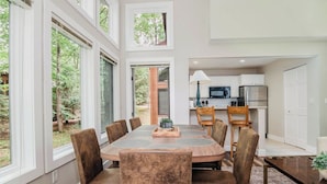 Uma sala de jantar com uma mesa redonda, seis cadeiras e vista para o exterior.