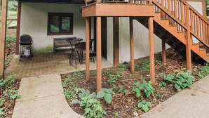 Uma casa de dois andares com deck de madeira, varanda coberta e escada.