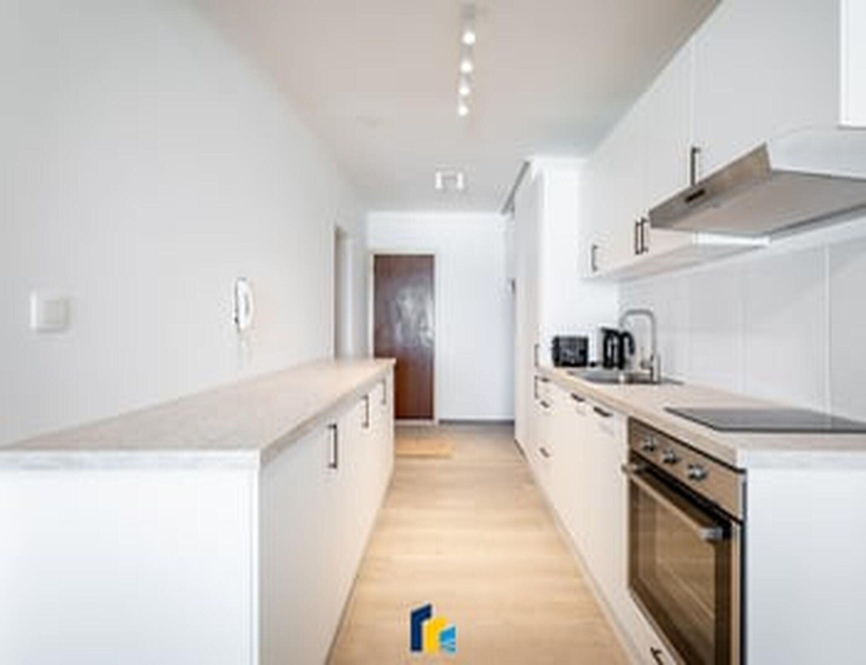 A modern kitchen with white cabinetry, a wooden countertop, and a built-in oven.