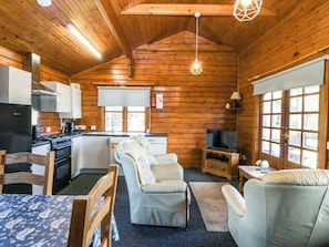 A log cabin interior with a kitchen, dining area, and seating. - Lodge 5 - Bron Eifion (Criccieth)