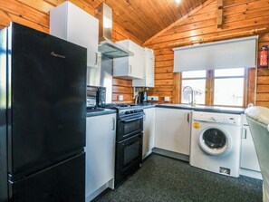 A compact kitchen with a refrigerator, stove, microwave, oven, and washing machine.