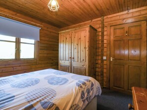 A wooden cabin room with a bed, a wardrobe, and a window. - Lodge 4 - Bron Eifion (Criccieth)