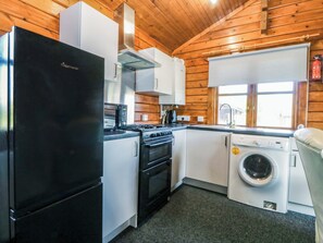 A compact kitchen with a refrigerator, stove, microwave, oven, and washing machine. - Lodge 4 - Bron Eifion (Criccieth)