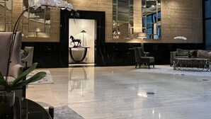 A spacious lobby with a polished floor, modern furniture, and decorative elements like orchids and mirrors. - The Gramercy Residences-58th floor w/balcony+Skyline view (Makati)