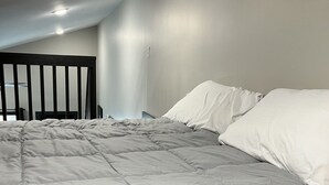 Een slaapkamer met een groot bed, hoofdbord en een plafondlamp.
