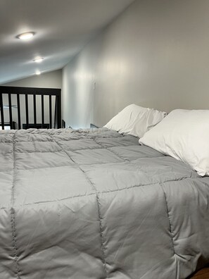 Una camera da letto con un grande letto, una testiera e una lampada a soffitto.