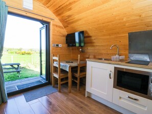 Una cocina compacta con paredes de madera, una mesa de comedor, sillas, un fregadero y un televisor.