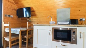 Cocina compacta con paredes de madera, microondas, tostadora y televisor sobre la encimera.