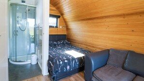A bedroom with a bed, a sofa, a shower, and a window. - Bron Eifion Pod 3 (Criccieth)