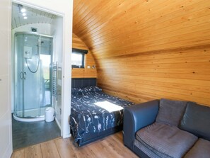 Ein Schlafzimmer mit Bett, einer Couch, einer Dusche und einem Fenster.
