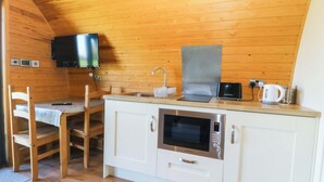 A compact kitchen with a microwave, sink, and a small television mounted on the wall. - Bron Eifion Pod 3 (Criccieth)