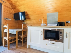 A compact kitchen with a microwave, a toaster, and a television mounted on the wall. - Bron Eifion Pod 3 (Criccieth)