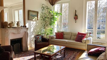 Un salon avec une cheminée, un canapé, une table basse et une grande fenêtre donnant sur un beau paysage.