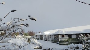 Een besneeerd landschap met een stenen gebouw, een houten hek en een sneeuwbedekte pad.