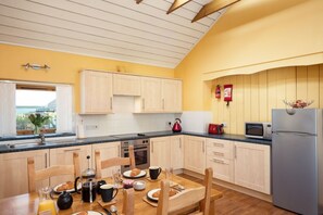 Eine Küche mit Holzausstattung, einem Edelstahlkühlschrank und einem Esstisch, der für das Frühstück gedeckt ist.